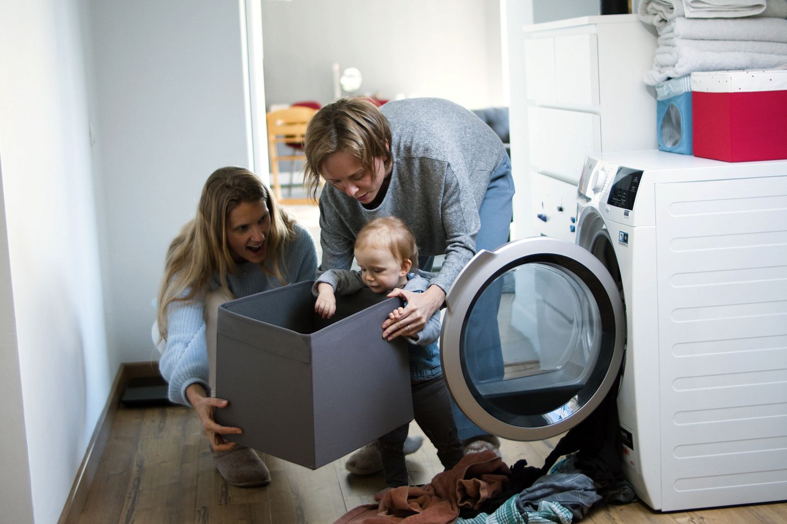 Parents sorting laundry at home with a baby beside them